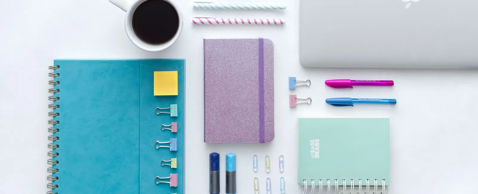 Laptop, notebooks and pens arranged on a white office desk