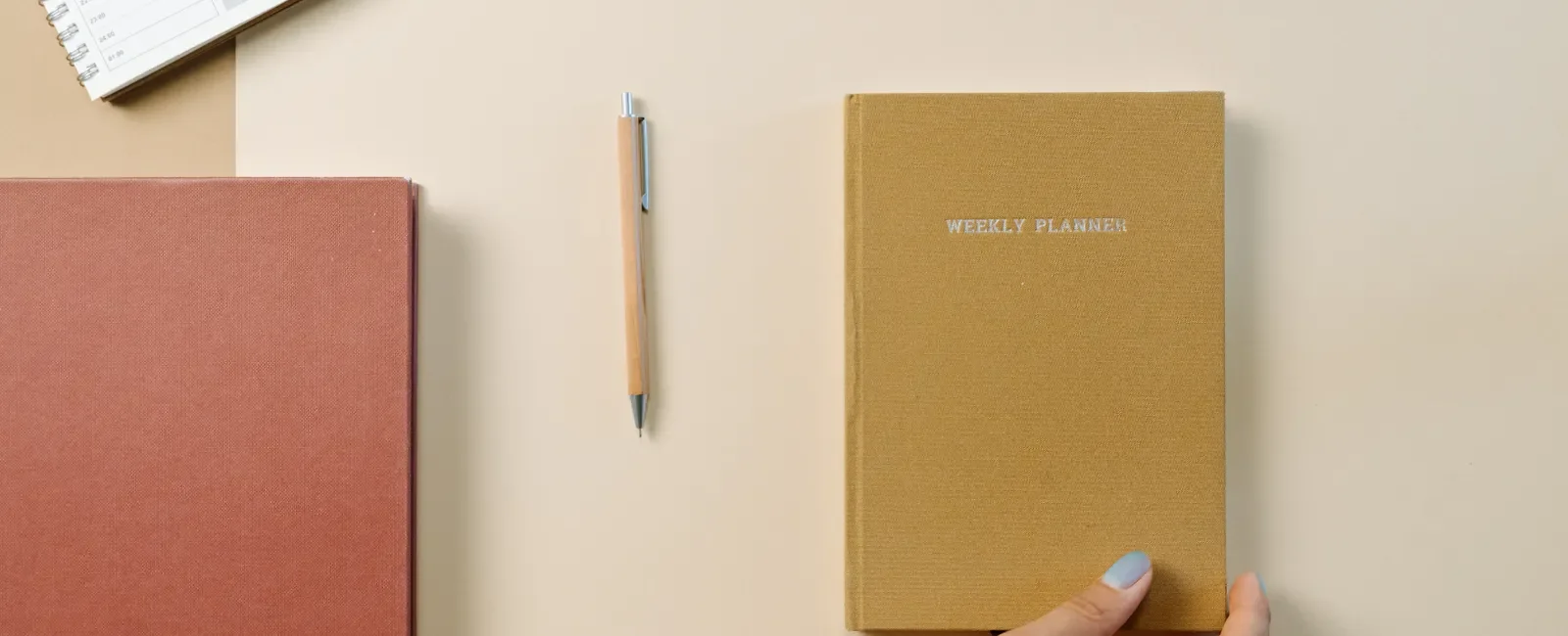 Weekly planner, open notebook and pen on a desk